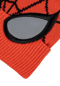 Primo piano di un guanto di lana arancione con un inserto per il palmo grigio imbottito, bordato di nero, e un motivo a rete nera sul tessuto.