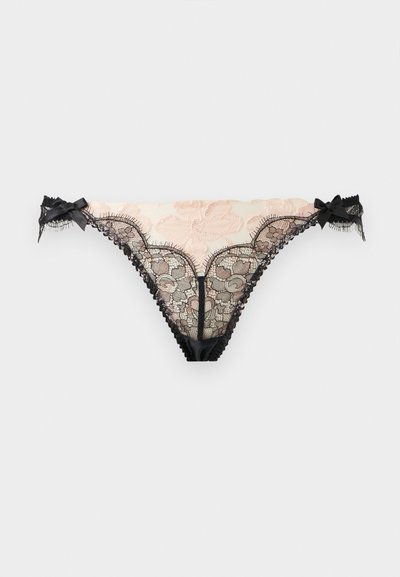 String en dentelle beige et noir pour femme avec broderie florale et petits nœuds décoratifs de chaque côté.