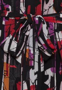 Cintura in tessuto a motivo astratto nei toni di nero, rosso, viola e bianco, con dettaglio a papillon, realizzata in un materiale leggero e con texture.
