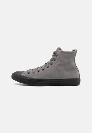 Szare trampki typu high-top z czarną podeszwą i noskiem, zapinane na sznurówki z przodu oraz miękką tkaninową wyściółką widoczną przy kołnierzu wokół kostki.