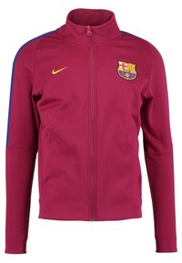 Veste de sport bordeaux avec col montant, fermeture éclair intégrale sur le devant, accents bleus sur les manches, et logo brodé de Barcelone sur la poitrine.