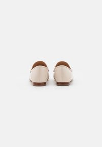 Kreemide nahast loafers ümmarguste varvastega, madala puidust kontsaga ja sileda tekstuuriga. Minimalistlik disain ilma nähtavate mustrite või riistvarata.