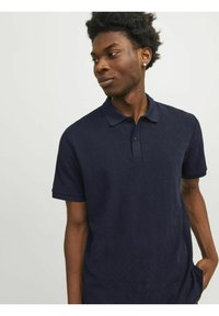 Camisa polo azul marino con un patrón geométrico texturizado, mangas cortas y un cierre con tres botones. Tejido de algodón suave, corte regular.