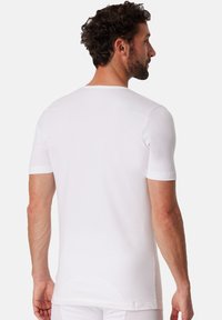Hvid kortærmet t-shirt lavet af glat bomuldsstof, med rund hals, tætsiddende design og en ensfarvet bagside uden udsmykninger.