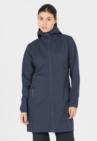Marinblå softshell-jacka med huva, framdragkedja och två sidofickor med dragkedja. Långa ärmar och en strömlinjeformad design med mjuk textur.