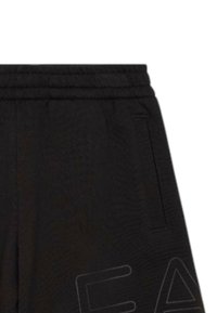 Pantaloni jogger neri con superficie testurizzata, vita elasticizzata, tasche laterali e un grande logo stampato su una gamba.