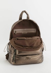 Sac à dos en bronze métallique avec un design matelassé. Comprend une poche zippée à l'avant, une poignée de transport sur le dessus et des bretelles ajustables. Texture lisse sur l'ensemble.
