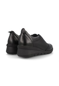 Zapatos de cuero negros con un diseño redondeado, que cuentan con una suela de cuña y acentos texturizados en la parte superior. Lengüeta trasera para ponerlos fácilmente.
