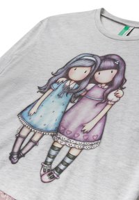 Camiseta gris con dos chicas de dibujos animados. Una tiene el cabello oscuro y lleva un vestido púrpura, mientras que la otra tiene el cabello azul y un vestido azul.