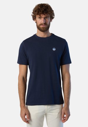 T-shirt in cotone blu navy con maniche corte e scollatura a girocollo, con un piccolo logo rotondo sul lato sinistro del petto. Texture liscia.