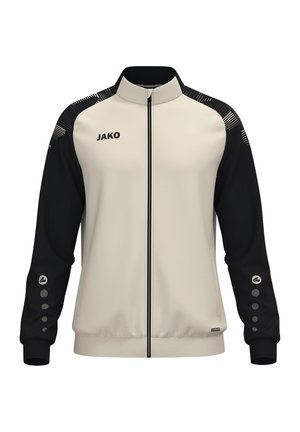 Beige og sort jakke med lynlås og høj krave, sorte ærmer med cirkulære ikoner, "JAKO" logo på venstre bryst og hvide striber på skuldrene.