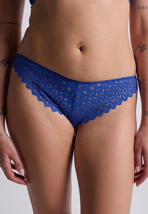 Des culottes en dentelle bleue présentant un motif floral avec des bords festonnés. Le tissu a une texture transparente, mettant en valeur des détails complexes tout au long.