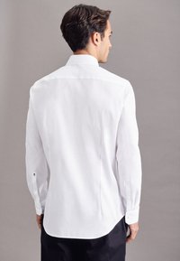 Witte lange mouw shirt met een rechte zoom en knoopmanchetten, met een klassieke kraag en subtiele branding op de mouwen.