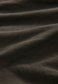 Tissu texturé marron foncé avec un petit motif de tissage visible et des plis doux créant des ombres douces.