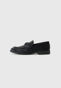 Loafers din piele neagră cu un finisaj neted, vârf ascuțit și o bandă pe vamp. Toc mic pătrat și detalii minime.