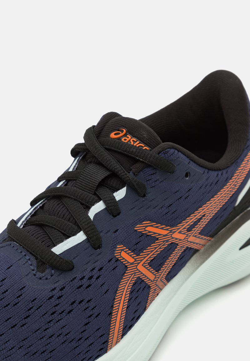 Baskets de course marines avec lacets noirs, accents orange, tige en maille et un motif texturé. Présente une semelle rembourrée et un design soutenant.