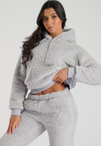 Grauer Fleece-Cropped-Hoodie mit strukturierten Oberflächen, halbseitigem Reißverschluss, Kängurutasche und gerippten Bündchen; kombiniert mit passenden Hosen.