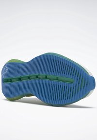 Semelle de chaussure présentant un design en caoutchouc bleu et vert avec des rainures et des crêtes texturées pour une meilleure traction, mettant en valeur l'épaisseur variable des matériaux.