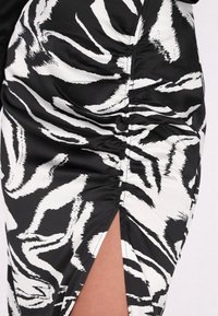Rochie cu imprimeu zebra alb-negru, cu o textură mătăsoasă, având pliu pe lateral și o fanta care se ridică până la coapsă.