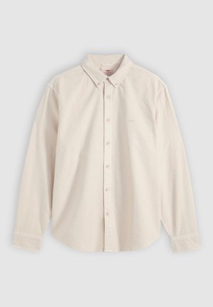 Μπεζ πουκάμισο με μακριά μανίκια και κουμπιά, με γιακά και μανσέτες, απλωμένο επίπεδα σε ανοιχτό γκρι φόντο.