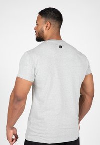 Grijs T-shirt met korte mouwen van katoen, met een ronde halslijn en een klein zwart logo op de achterkant van de hals.