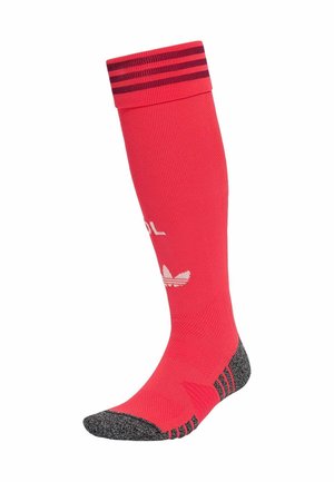 Calcetín deportivo rojo hasta la rodilla con puntera y talón negros, franjas negras en el puño y logotipo blanco de Adidas en la zona de la espinilla.