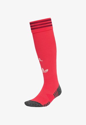 Calcetín deportivo rojo hasta la rodilla con puntera y talón negros, franjas negras en el puño y logotipo blanco de Adidas en la zona de la espinilla.