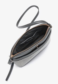 Svart läder crossbody-väska med en vävd grå utsida, gyllene dragkedja och svart tyginredning som har en ficka och rem.