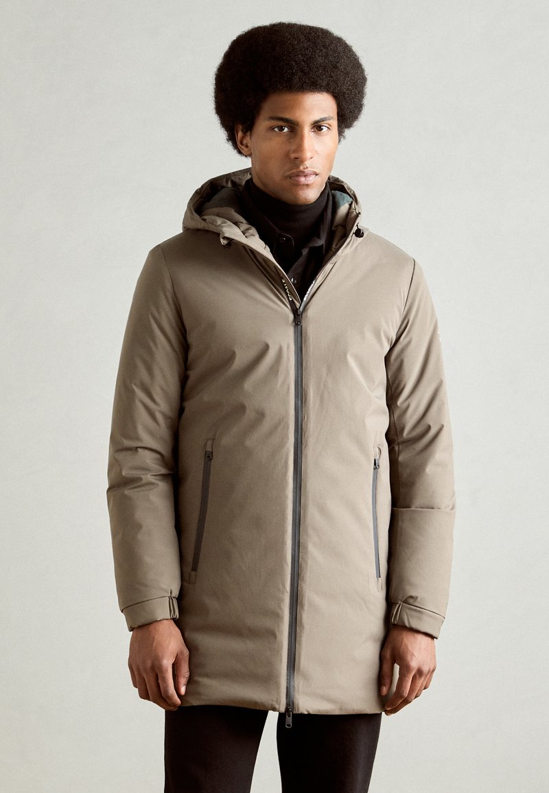Parka beige con capucha, cierre frontal, dos bolsillos laterales y puños elásticos. Material suave con acabado mate.