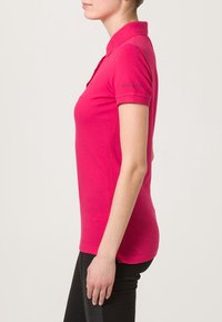 Tajtat rosa pikétröja i bomull med krage och korta ärmar, med diskreta sömdetaljer och en logotyp på ärmen.