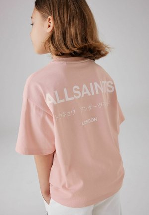 Lyhythihainen vaaleanpunainen puuvillapaita, jossa on suuri valkoinen teksti selässä, mukaan lukien "ALLSAINTS" ja sen alla "LONDON".