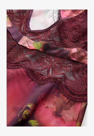 Koronkowa bluzka w kolorze burgundowym z przezroczystą warstwą, z delikatnym kwiatowym wzorem i teksturowanym koronkowym wykończeniem.