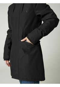 Juodas vandeniui atsparus džemperis turi priekinį užtrauktuką, kišenes ir kapišoną. Audinys atrodo lygus, su sustiprinta siuvimo siūle.