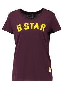 Camiseta de algodón morada de manga corta que presenta un gran texto amarillo "G-STAR" en la parte frontal y una pequeña etiqueta en la costura inferior izquierda.