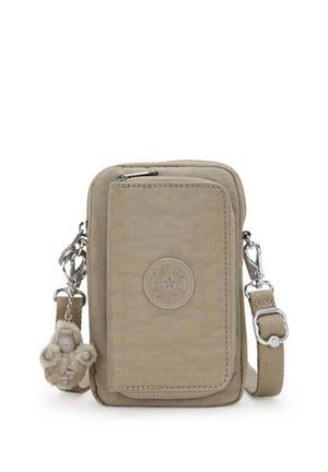 Sac bandoulière beige à texture lisse, avec une poche zippée à l'avant, un patch logo, et un pendentif orné d'une figurine en laine.