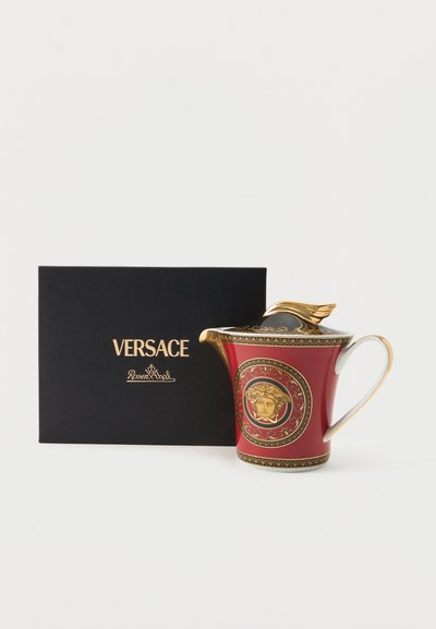 Κόκκινος και χρυσός τσαγιέρα Versace Rosenthal με έμβλημα Μέδουσας δίπλα σε μαύρο κουτί με την επωνυμία Versace Rosenthal σε λευκό φόντο.