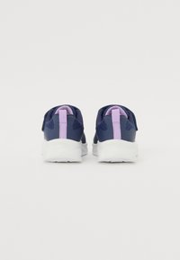 Zapatillas navy con parte superior de malla texturizada, acentos morados y suela blanca. Cuenta con un collar acolchado y una lengüeta para ponerse con facilidad.