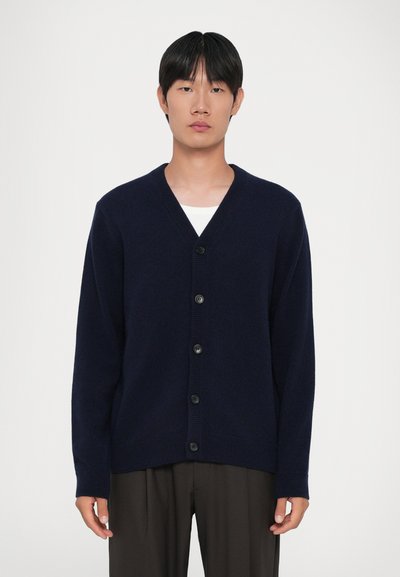 Marineblaue Strickjacke aus Nacken, mit V-Ausschnitt, langen Ärmeln und sechs schwarzen Knöpfen auf der Vorderseite, sowie gerippten Bündchen und Saum.