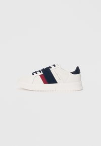 White sneaker with navy and burgundy stripes, fabric upper, rubber sole, round toe, and dark blue laces. Minimalist design and branding.