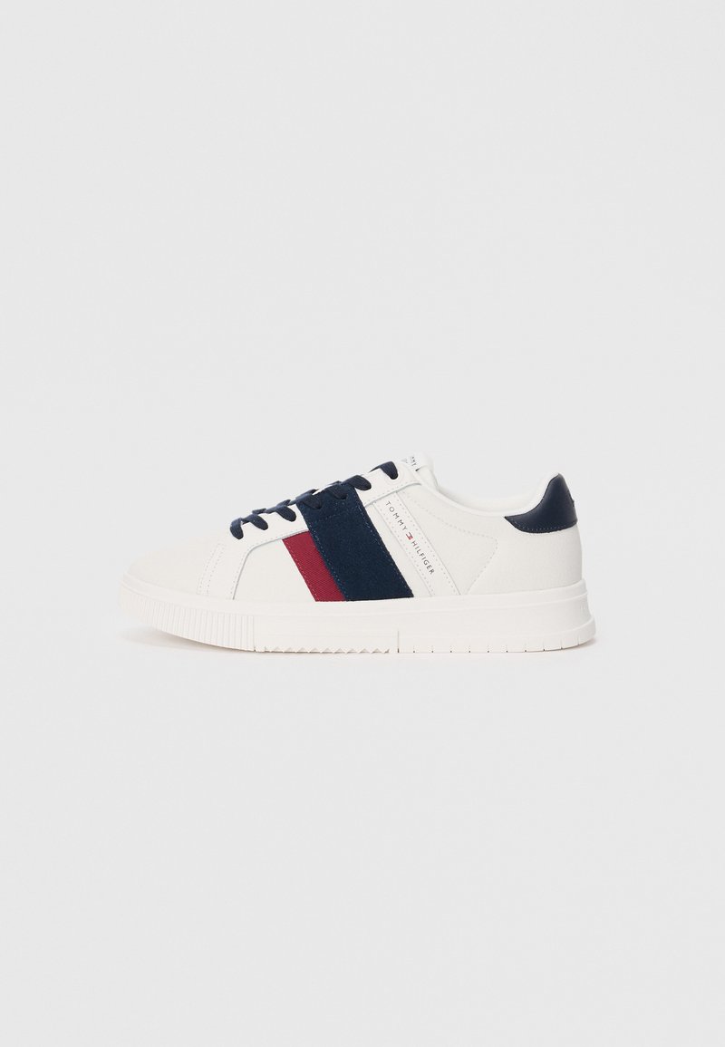 White sneaker with navy and burgundy stripes, fabric upper, rubber sole, round toe, and dark blue laces. Minimalist design and branding.