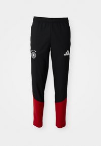 Melnas sporta bikses ar sarkanajiem apakšējiem kājiem, elastīga josta, Adidas logo labajā augšstilbā un Vācijas futbola komandas emblēma kreisajā augšstilbā.