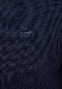 Marineblauer strukturierter Stoff mit einem dezenten, gestickten Pferdelogo in einem etwas helleren Blauton.