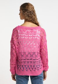 Suéter de punto rosa con un patrón de encaje abierto, mangas largas y dobladillo acanalado. Presenta un escote amplio y detalles de textura visibles.