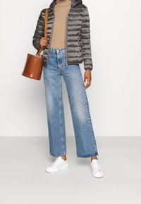Gray puffer jacket with a hood; tan turtleneck; wide-leg blue jeans; white sneakers; brown bucket bag. Casual outfit with textured materials.