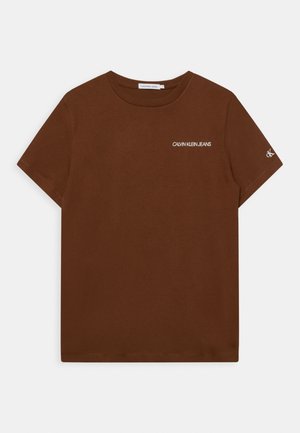 Camiseta marrón de manga corta con cuello redondo, con el texto "Calvin Klein Jeans" en el pecho y un pequeño logo "CK" en la manga derecha.