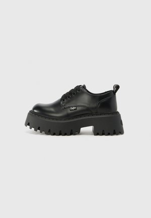 Sapatos de plataforma pretos feitos de couro liso, com sola grossa e texturizada e bico arredondado. Possui seis ilhós e uma alça de puxar.