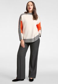 Pullover-Pullover in Creme, Grau und Orange mit hohem Kragen; kombiniert mit grauen, weit geschnittenen Hosen; einfarbig, weiche Textur und entspannte Passform.