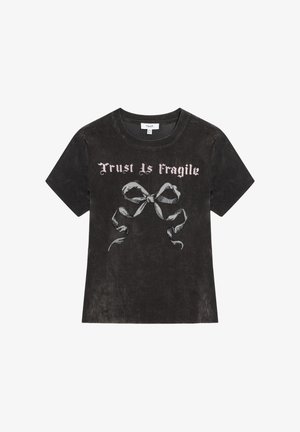 T-shirt en coton noir avec col rond, manches courtes, et impression décolorée d'un ruban et du texte « La confiance est fragile » en rose clair.