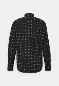 Czarna koszula z powtarzającym się białym i kremowym wzorem geometrycznym, długimi rękawami i kołnierzykiem band. Gładka faktura materiału, zaokrąglony dół.