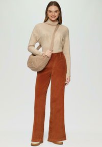 Beige gestreifter Rollkragenpullover, rostfarbene Cordhose mit weitem Bein und eine tanfarbene strukturierte Schultertasche. Schuhe mit dicker Sohle in passender Farbe.